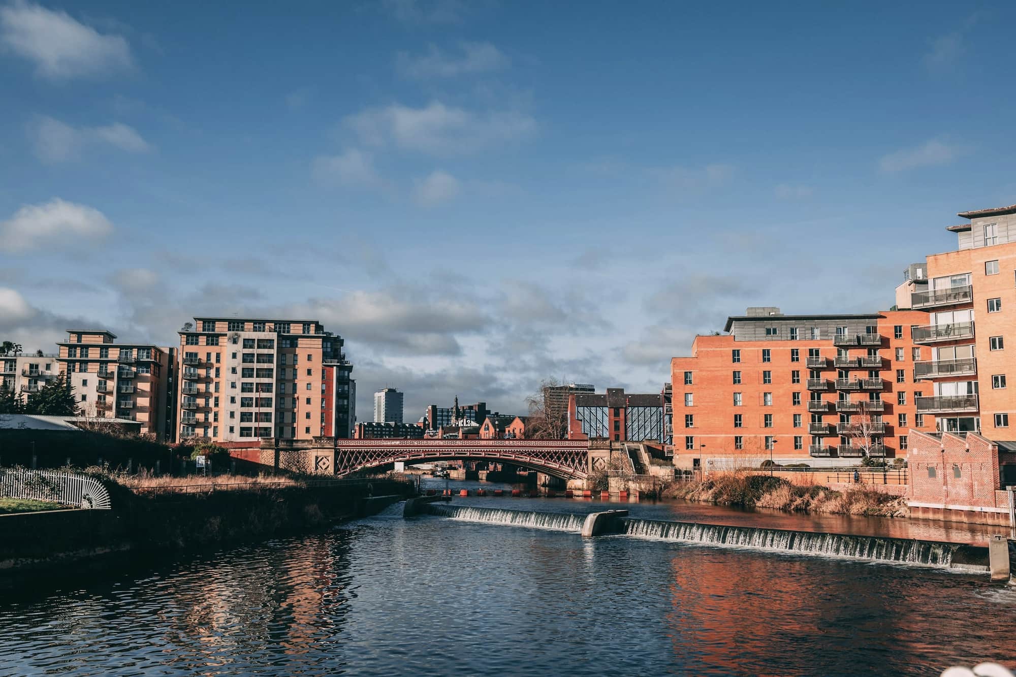 The River Aire in Leeds, with a low weir and red-brick apartment buildings on both banks