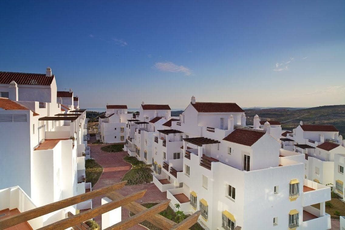 Rooftops of a whitewashed apartment complex looking out towards the sea
